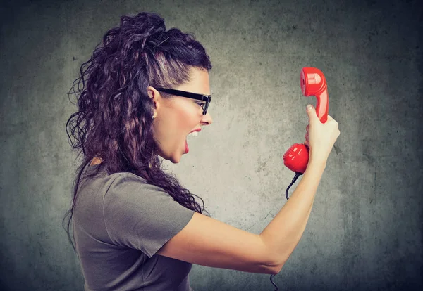 Mujer sosteniendo receptor de teléfono rojo y gritando de rabia . —  Fotos de Stock