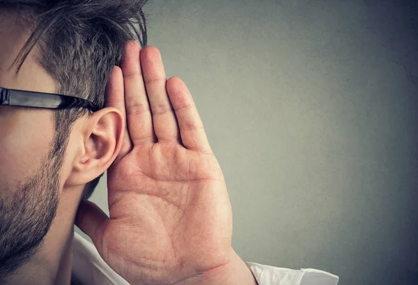 El hombre sostiene su mano cerca de la oreja y escucha con atención —  Fotos de Stock