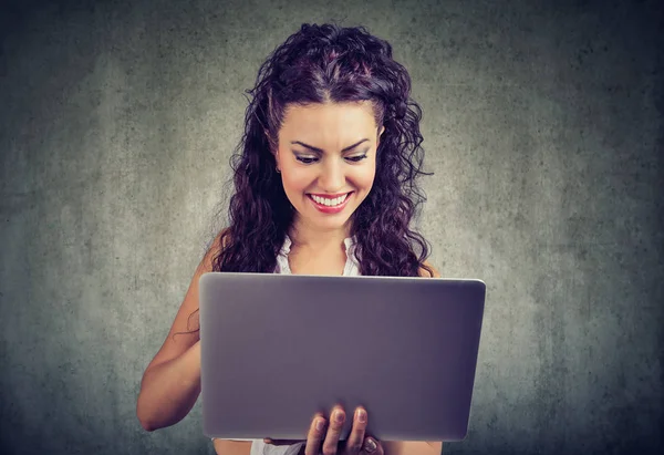Cheerful young woman holding and using laptop — Stock Photo, Image