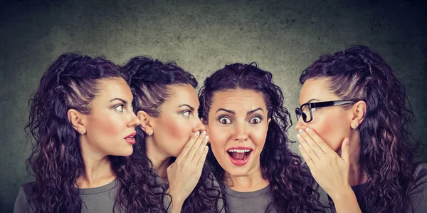 Three young women whispering each other and to a shocked astonished girl — Stock Photo, Image