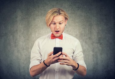 Akıllı telefonuna bakan adamın yüzünde şaşırmış bir ifade var..