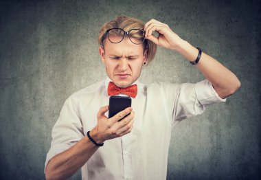 Gözlüklü genç adam görme sorunu olduğunda cep telefonu kullanıyor.