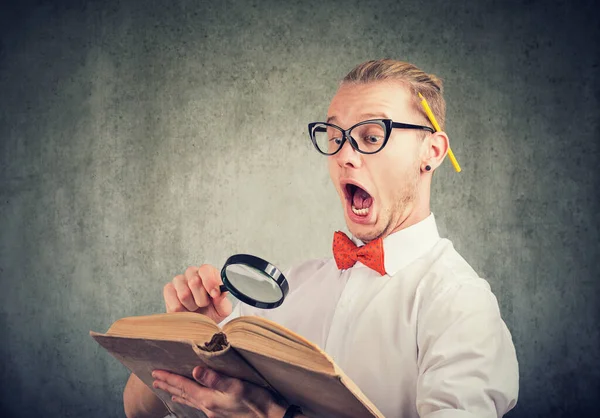 Shocked Young Man Magnifying Glass Reading Ancient Book Feeling Amazed — Stock Photo, Image