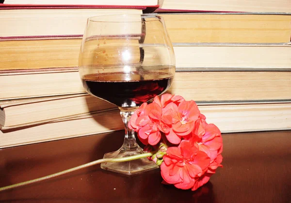 Kırmızı şarap kadehi ve kitaplar masanın üstünde.