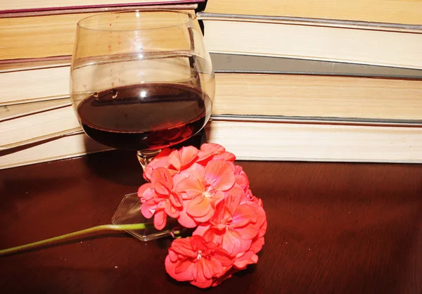 Kırmızı şarap kadehi ve kitaplar masanın üstünde.