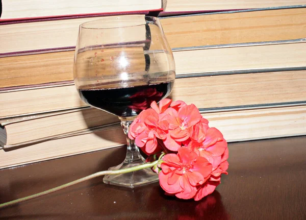 Kırmızı şarap kadehi ve kitaplar masanın üstünde.