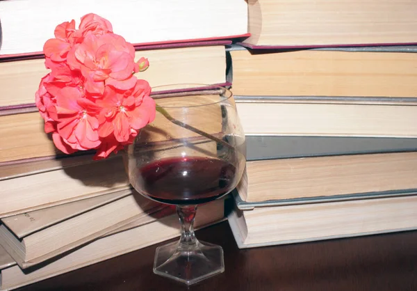 Kırmızı şarap kadehi ve kitaplar masanın üstünde.
