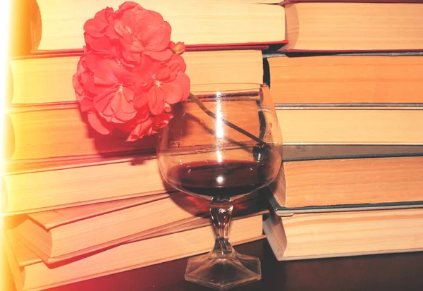 Kırmızı şarap kadehi ve kitaplar masanın üstünde.