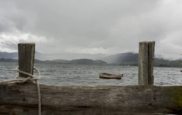 The boat docked at the lake dock. The tide is low and everything is too calm.