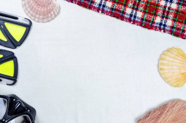 İki deniz kabuğu kauçuk yüzgeçli siyah maske, kireçtaşı dalışı ve köşelerdeki kareli plaj paspası için açık kumaştan arka plan görüntüsü metin için alanı kapat