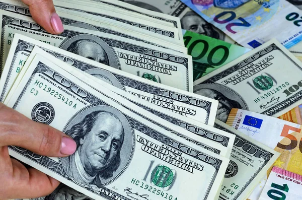 ユーロとドルの背景に女性の手に保持している米国の100ドル紙幣の束 — ストック写真