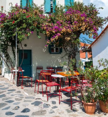 Yunanistan 'ın başkenti Nothe Sporades' te çiçek açan bougainvillea ile süslenmiş küçük bir Yunan kafesi.