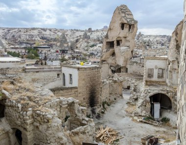 İçinde güvercin mağarası ve terk edilmiş ev bahçesi olan çökmüş kaya sütununun yatay görüntüsü, Türkiye 'nin Kapadokya bölgesindeki Goreme şehrindeki hasarlı duvarlar