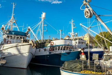 Mavi gökyüzüne karşı demirli balıkçı teknelerinin ve rüzgarların manzarası