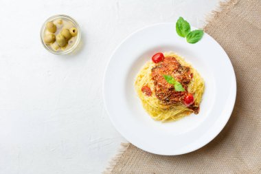 Domates soslu İtalyan makarnası, fesleğen yaprağı, zeytin. Beyaz beton arka plan ve çuval bezi üzerinde duruyor. Yatay olarak. Üst Manzara. Boşluğu kopyala