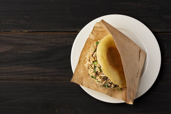 Roujiamo chinese hamburger in white plate on a balck wooden table.