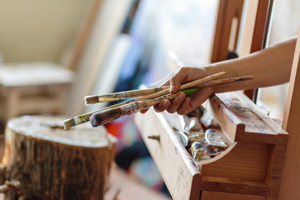 Artist's hand with brushes for painting on easel