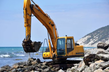 Kazıcı deniz sahilini temizliyor.