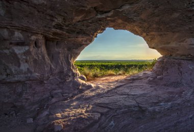 Brezilya 'nın Jalapao kentindeki kayalık delikten (Pedra furada) gün batımı manzarası. Jalapao cazibelerinden biri olan Pedra furada, zaman içinde rüzgarın etkisiyle aşınmış bir arenit kayasıdır..