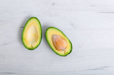 Dilimlenmiş avokado, açık ahşap bir masada kemiğe yakın çekim. Sağlıklı beslenme. Çok olgun bir avokado..