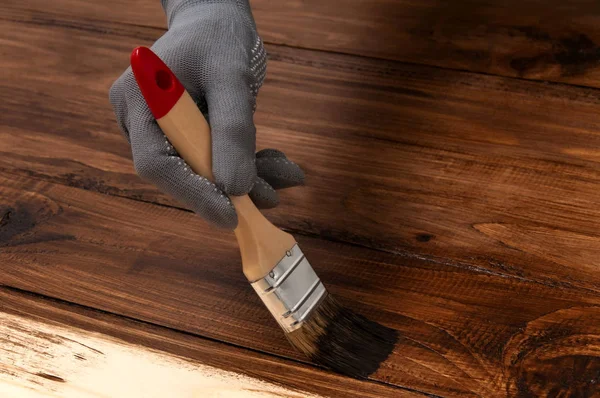 Kız kahverengi boyayla resim çiziyor. Elinde fırça olan bir kız ahşap tahtalar boyuyor. Bir adam fotofon yapar. Adam ahşap bir yüzey boyuyor. Yarı boyanmış masa.