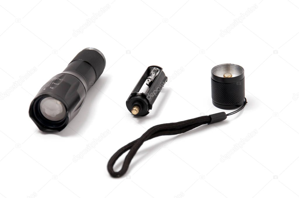 Small black pocket lamp on a gray wooden table on a white background. Turned off flashlight close-up on a light background. Disassembled flashlight.