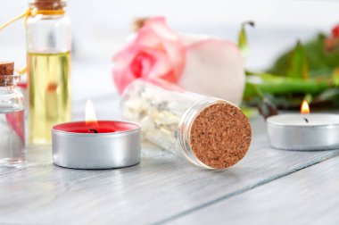 Pembe güller, yağ şişeleri ve gri ahşap bir masada yanan mumlar. 8 Mart. Sevgililer Günü. Tebrik kartı. Romantik ve güzel bir geçmişi var. Spa tedavileri. Kişisel bakım. Aşk ve güzellik.