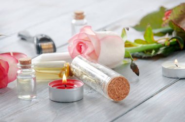 Pembe güller, yağ şişeleri ve gri ahşap bir masada yanan mumlar. 8 Mart. Sevgililer Günü. Tebrik kartı. Romantik ve güzel bir geçmişi var. Spa tedavileri. Kişisel bakım. Aşk ve güzellik.