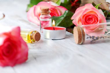 Pembe güller, yağ şişeleri ve gri ahşap bir masada yanan mumlar. 8 Mart. Sevgililer Günü. Tebrik kartı. Romantik ve güzel bir geçmişi var. Spa tedavileri. Kişisel bakım. Aşk ve güzellik.