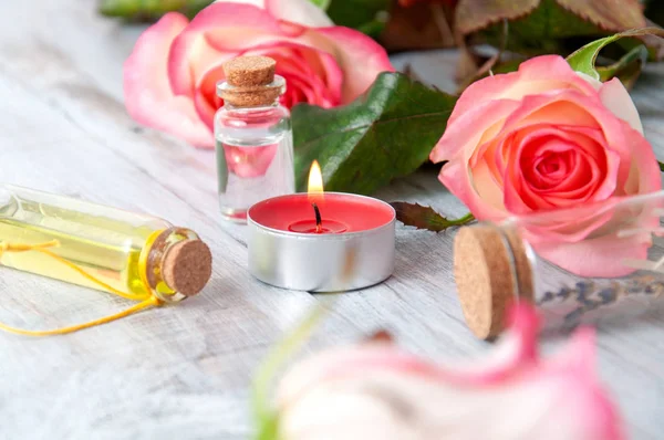 Rosas Cor Rosa Garrafas Óleo Velas Acesas Uma Mesa Madeira — Fotografia de Stock