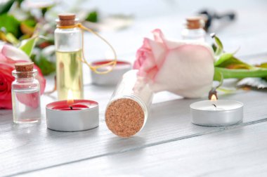 Gri ahşap bir masada pembe güller, yağ şişeleri ve mumlar. 8 Mart. Sevgililer Günü. Tebrik kartı. Romantik ve güzel bir geçmişi var. Spa tedavileri. Kişisel bakım. Aşk ve güzellik.