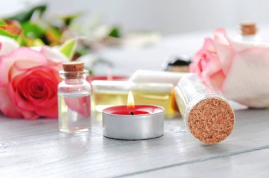 Pembe güller, yağ şişeleri ve gri ahşap bir masada yanan mumlar. 8 Mart. Sevgililer Günü. Tebrik kartı. Romantik ve güzel bir geçmişi var. Spa tedavileri. Kişisel bakım. Aşk ve güzellik.