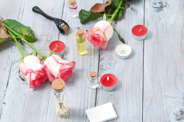 Pembe güller, yağ şişeleri ve gri ahşap bir masada yanan mumlar. 8 Mart. Sevgililer Günü. Tebrik kartı. Romantik ve güzel bir geçmişi var. Spa tedavileri. Kişisel bakım. Aşk ve güzellik.