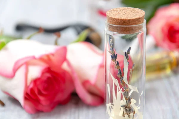 Pink roses, oil bottles and candles on a gray wooden table. March 8. Valentine's Day. Greeting card. Romantic and beautiful background. Spa treatments. Personal care. Love and beauty.