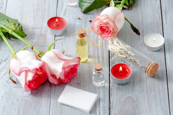 Rosas Rosadas Botellas Aceite Velas Encendidas Una Mesa Madera Gris — Foto de Stock