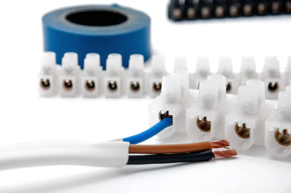 Terminal blocks, three-wire cable and electrical tape on a white isolated background.