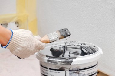 Kız duvarı griye boyuyor. Odada onarım var. DIY onarımı.