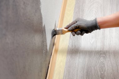 Kız duvarı griye boyuyor. Odada onarım var. DIY onarımı.