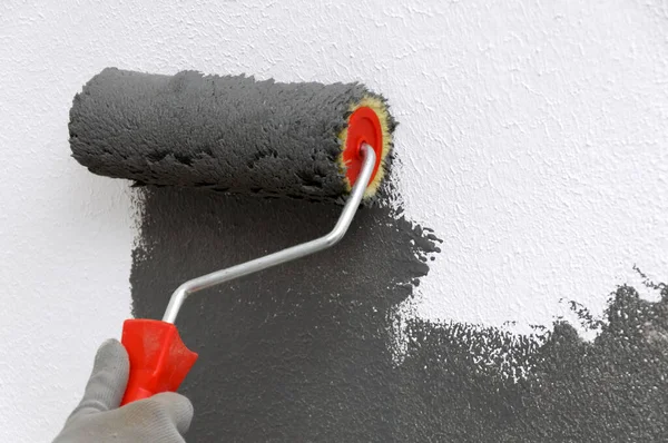 Kız yakın planda bir patenci tutuyor. Kız duvarı griye boyuyor. Odada onarım var. DIY onarımı.