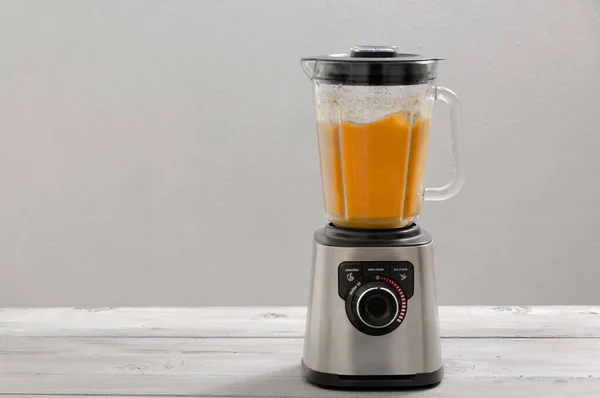 Blender, havuç, maydanoz, gri ahşap bir masada dereotu. Kız sebze püresi yapıyor. Sağlıklı bir yaşam tarzı. Beslenme düzeni. Havuç ve yeşillik yakın plan..