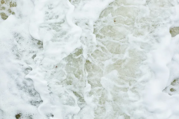 Mousse blanche causée par une action des vagues — Photo