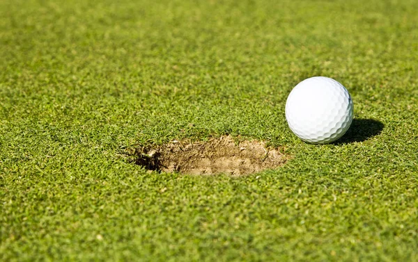 Bola de golfe ao lado da taça — Fotografia de Stock