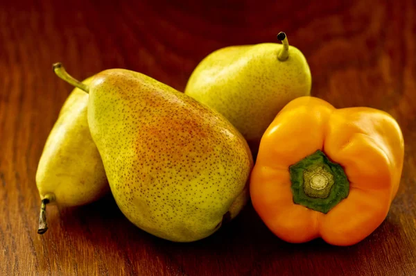 Pere e un pepe giallo su uno sfondo di legno — Foto Stock