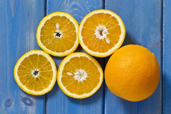 青い木製の背景にオレンジをスライス — ストック写真