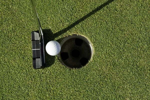 Golf putter och bollen bredvid koppen — Stockfoto