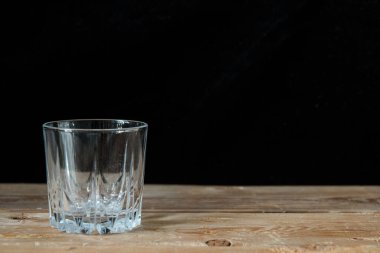Tahta masadaki su için cam, siyah arkaplan ve metin için boş alan.
