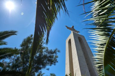 İsa 'nın heykeli aşağıdan palmiye dallarının arasından gün ışığına bakıyor. Almada Lizbon Portekiz