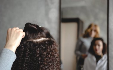 Saç stiline odaklan. Arkaplan resmi. Bulanık arka plan, bir kız ve bir kuaför aynada saçlarını kontrol ediyor..