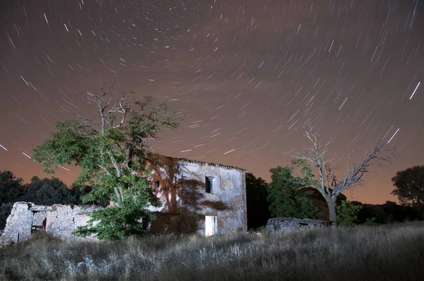 Yıldızlı gökyüzü ve arka planda terk edilmiş bir ev.