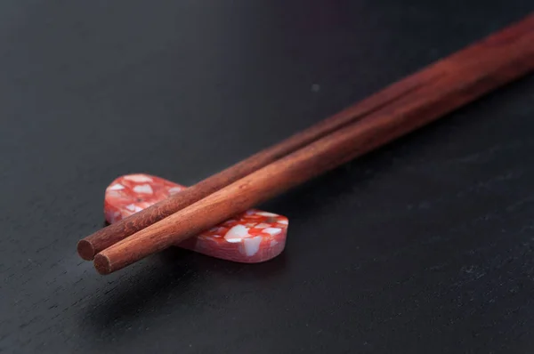 Ahşap çubuklar koyu arkaplanı olan renkli taşların üzerinde dururlar. Kapat..